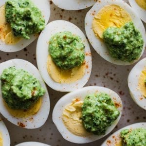 hard boiled eggs on a plate with pesto on top