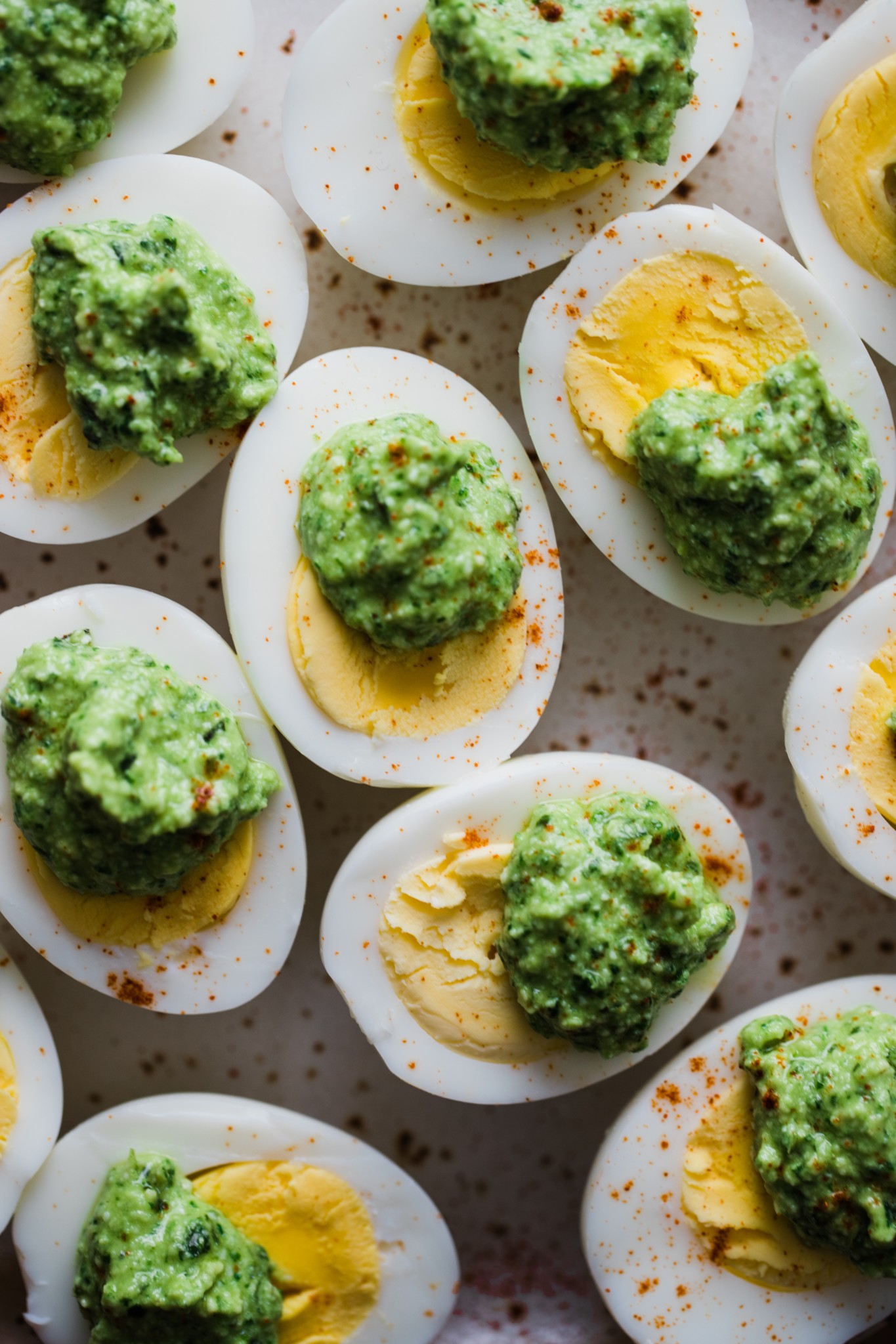 hard boiled eggs on a plate with pesto on top