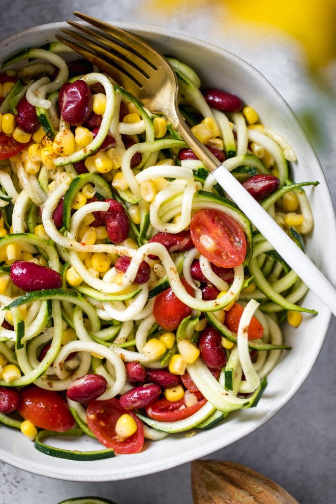 zoodle salad with corn in a white bowl