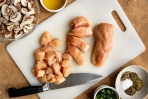 dicing raw chicken on cutting board