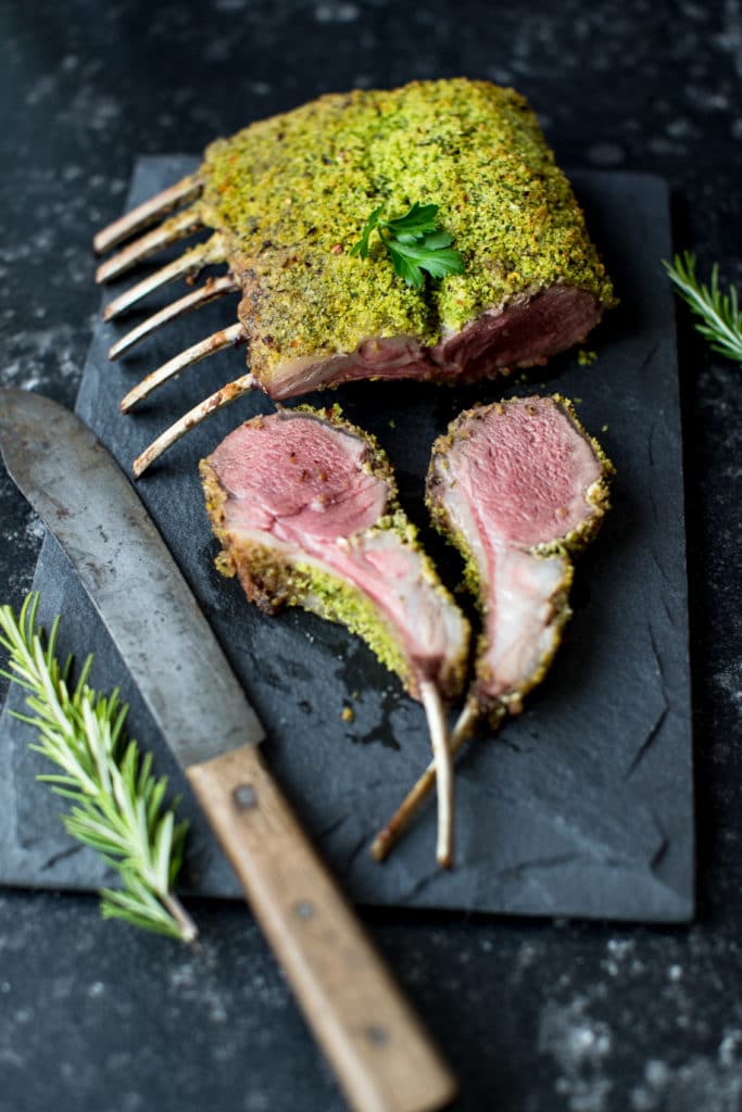 herb crusted rack of lamb with a knife on a black slate