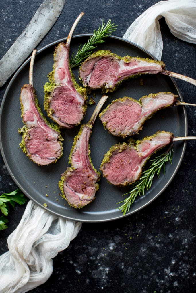 herb crusted rack of lame on a dark blue plate