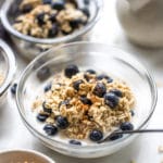 overnight oats made with oat milk topped with blueberries in glass bowls