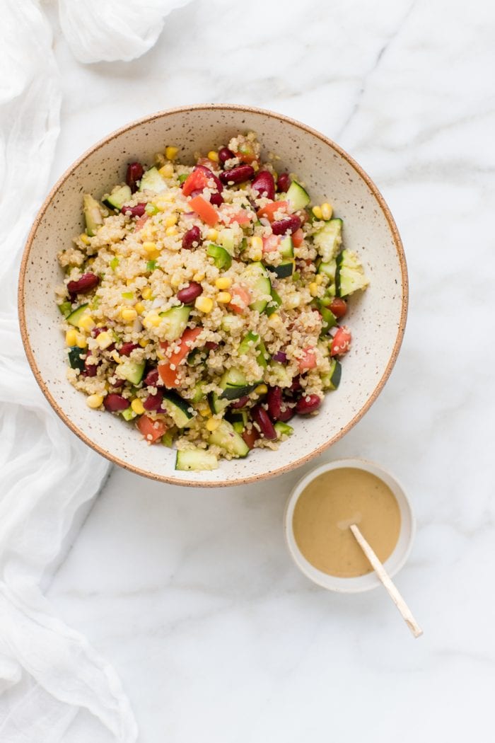 quinoa in a bowl with fresh veggies and a tahini lemon dressing