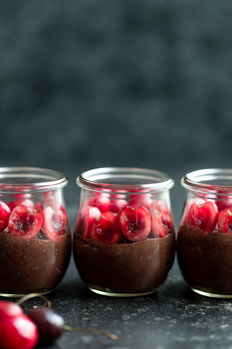 chocolate mousse in glass jars topped with cherries