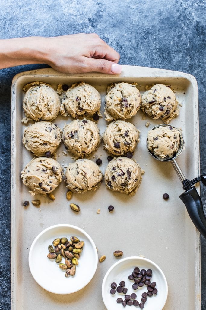 chocolate chip cookie dough with pistachios and cranberries on a baking sheet