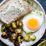 pork chops, eggs and Brussels sprouts on a white plate