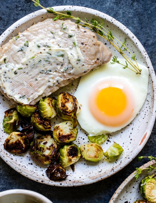 pork chops, eggs and Brussels sprouts on a white plate