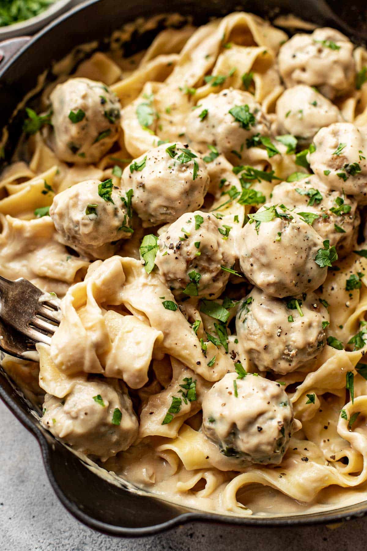 swedish meatballs with pasta garnished with parsley in a skillet. 