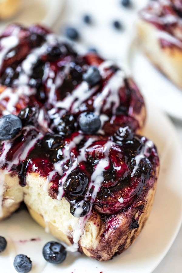 cinnamon rolls from scratch with blueberry sauce on top on a white plate