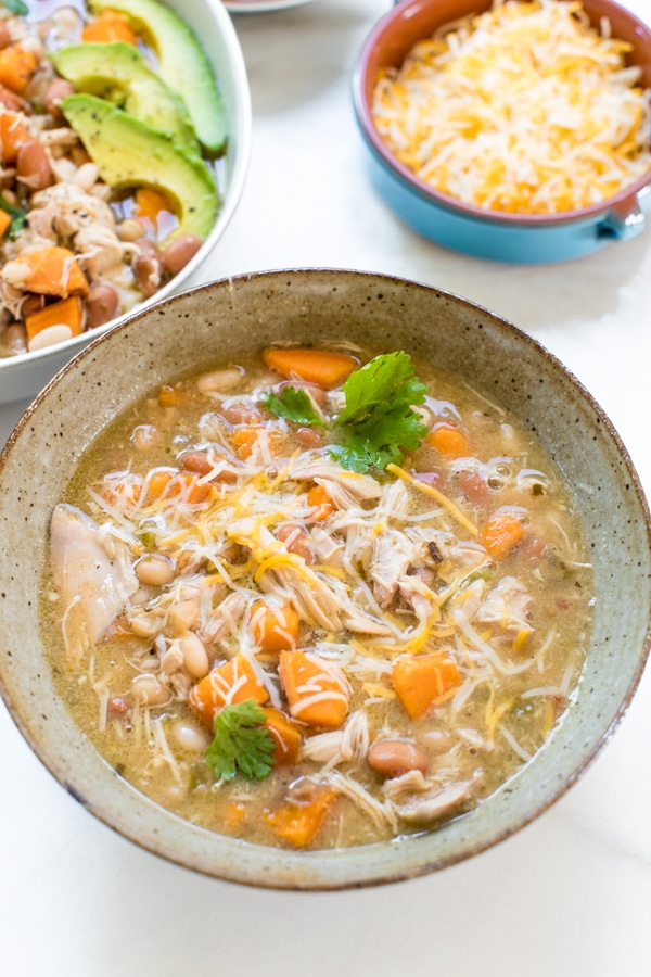 Slow Cooker green and white chicken chili garnished with avocado and sour cream