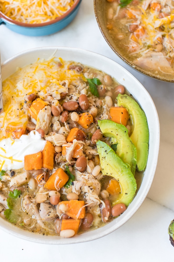 Slow Cooker green and white chicken chili garnished with avocado and sour cream