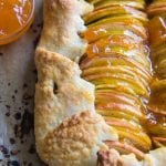 a baked apple galette on parchment paper with apricot jam