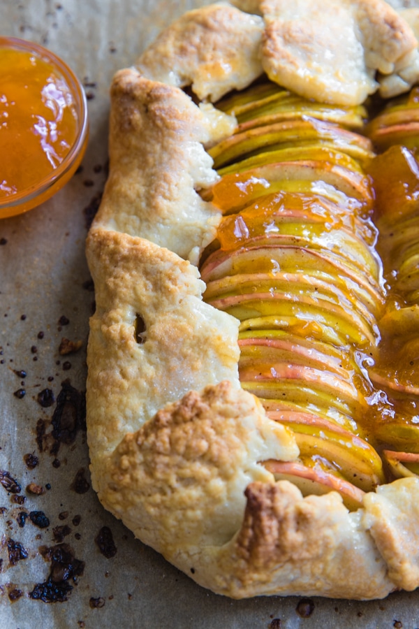 a baked apple galette on parchment paper with apricot jam