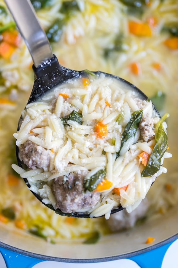 Italian Wedding Soup made with Orzo being ladled out of a blue stock pot