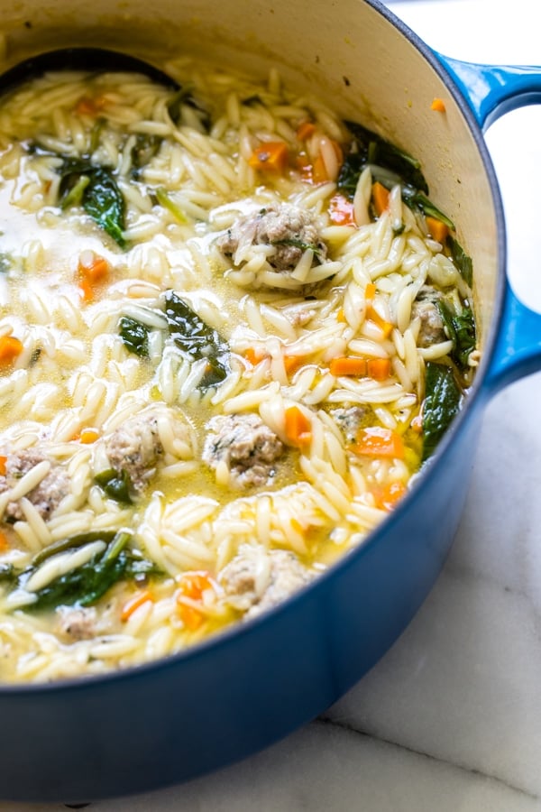 Italian wedding soup recipe made with beef and pork meatballs in a large blue stock pot.