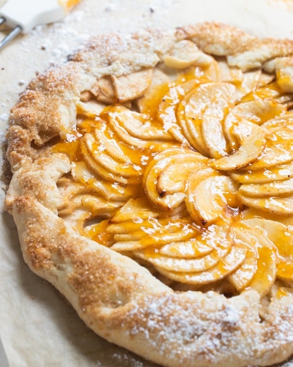 a baked apple galette on parchment paper with apricot jam