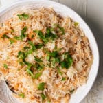 rice pilaf in a white bowl topped with fresh parsley