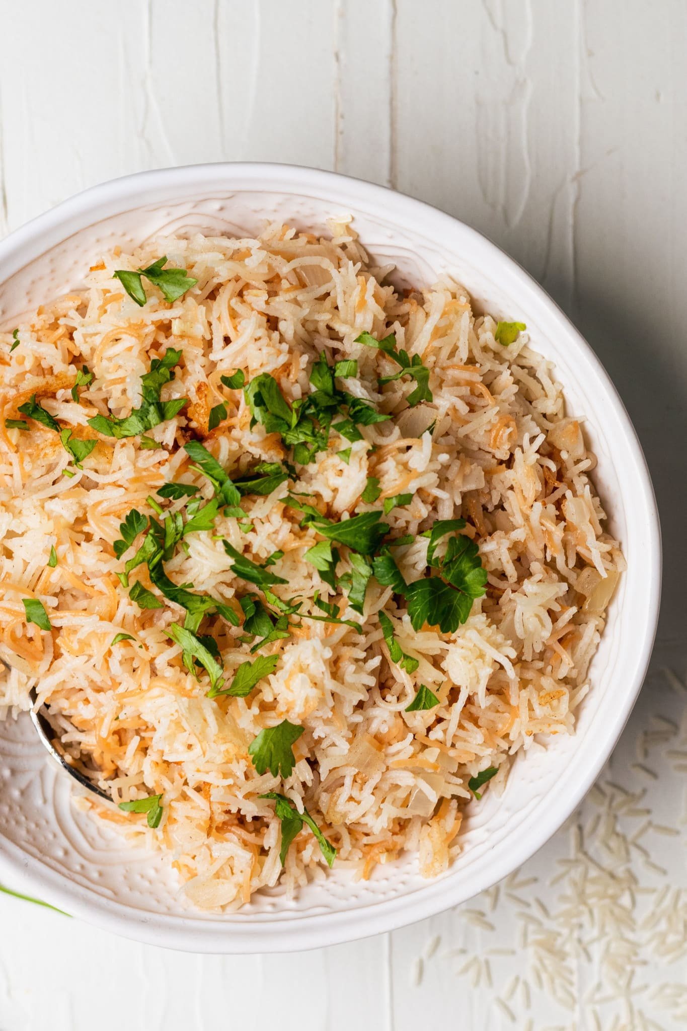 rice pilaf in a white bowl topped with fresh parsley