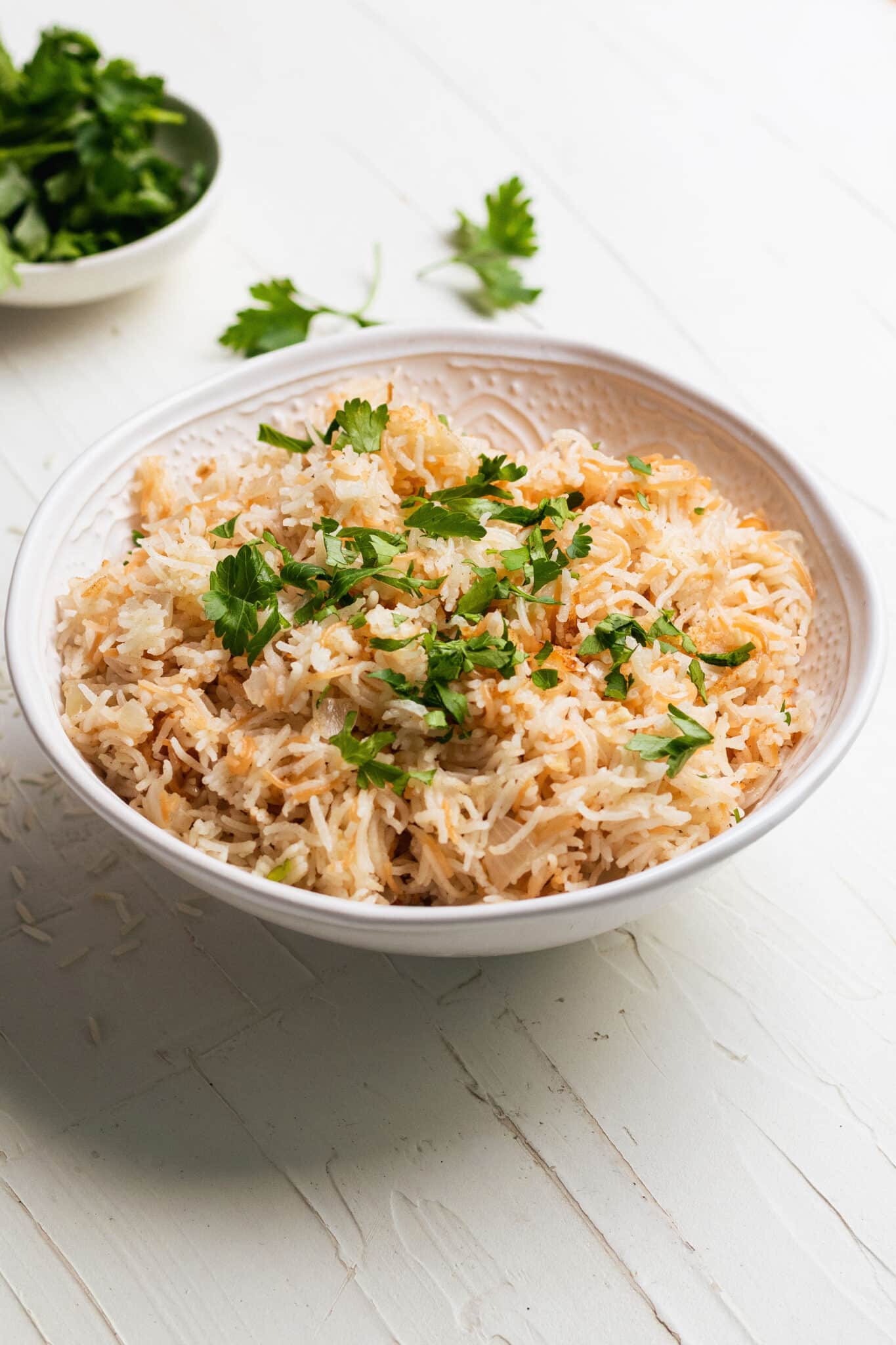 rice pilaf in a white bowl topped with fresh parsley