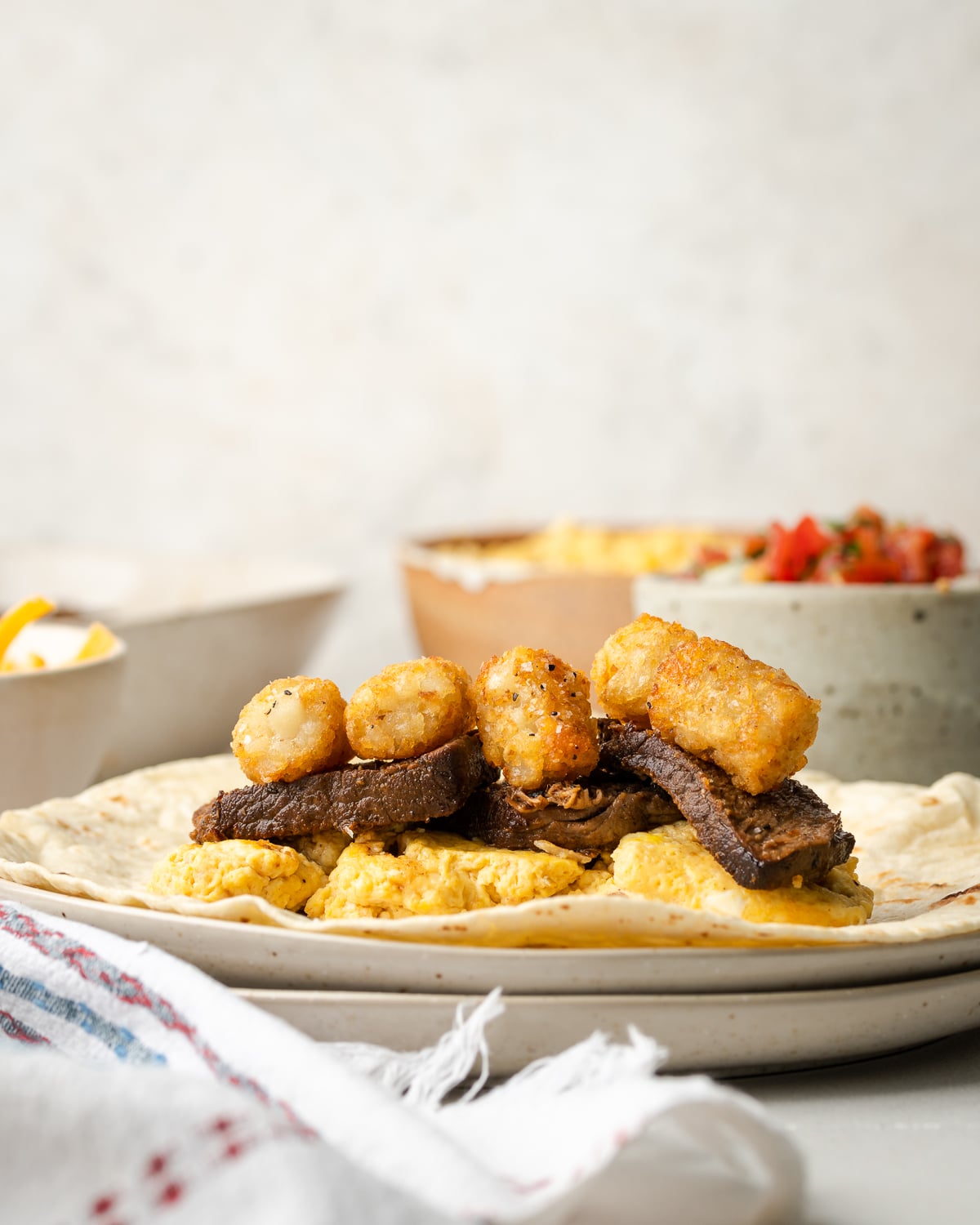 tater tots on top of steak and eggs on a flour tortilla
