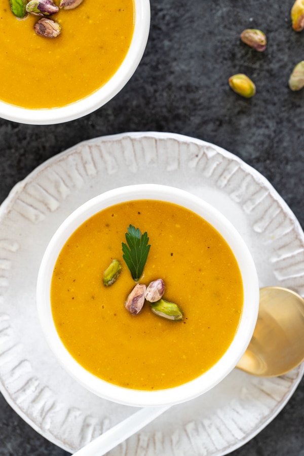 pistachio pumpkin soup in small white bowls topped with pistachios 