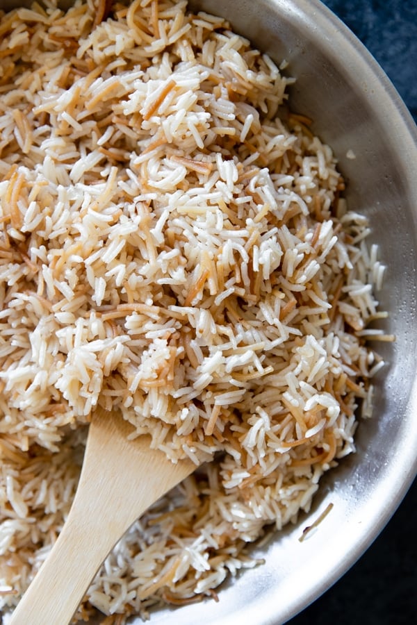 rice pilaf freshly made in a saute pan with a wooden spoon scooping some out