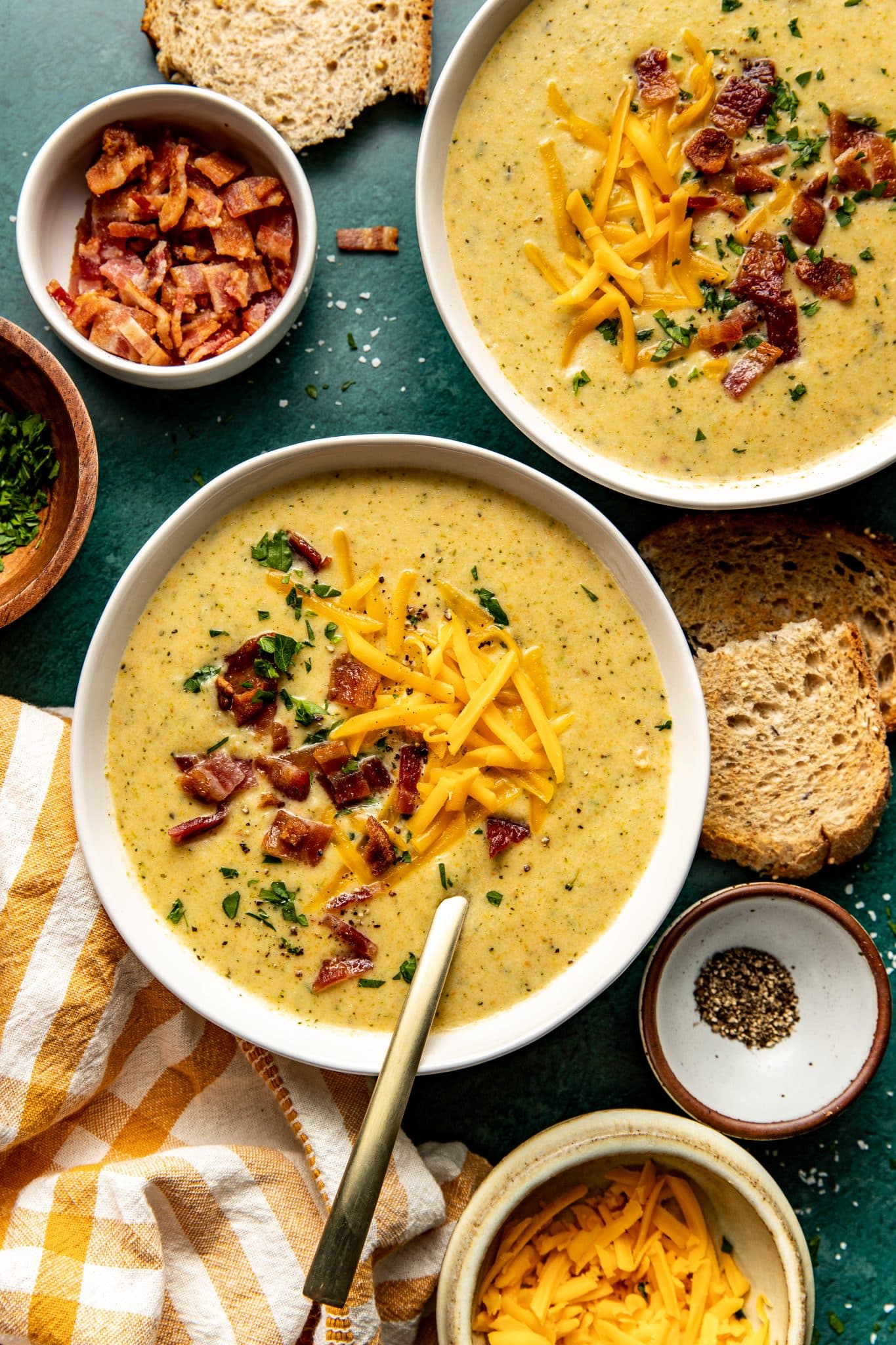 broccoli soup in white bowls topped with crispy bacon and cheddar cheese. 