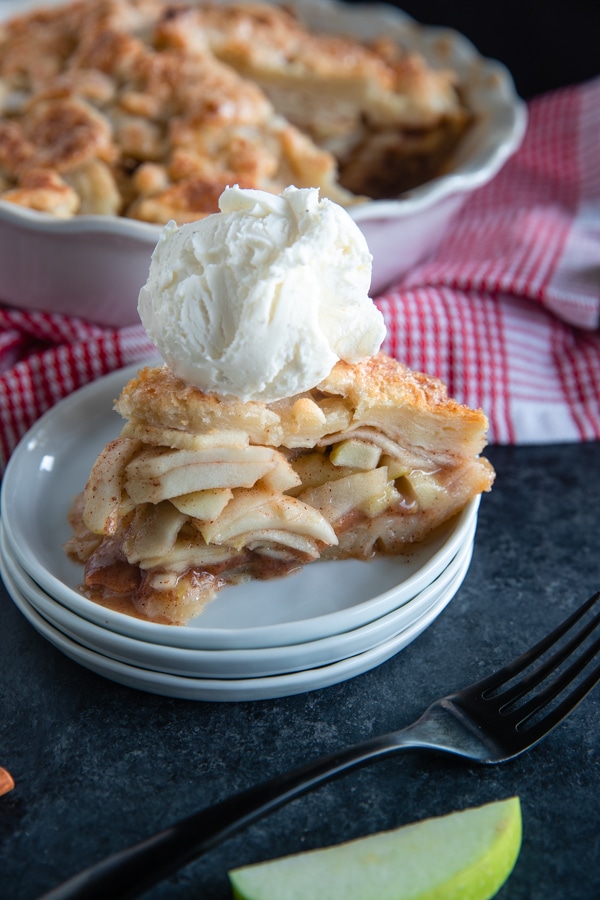 apple pie on a white plate with vanilla ice cream on top