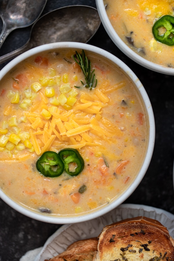 corn chowder in a white bowl topped with cheese