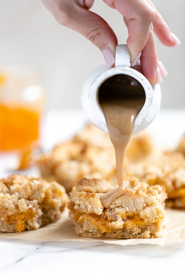 homemade apricot bars on a marble board being drizzled with caramel