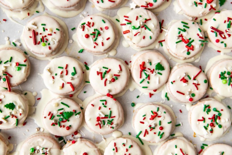 ritz cracker cookies with white icing and christmas sprinkles on parchment paper