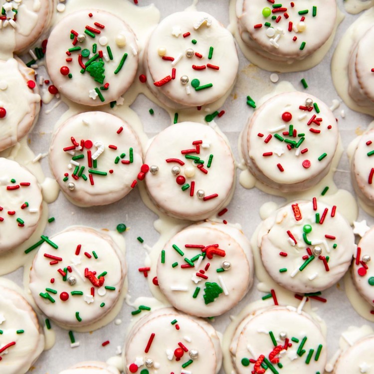 ritz cracker cookies with white icing and christmas sprinkles on a sheet