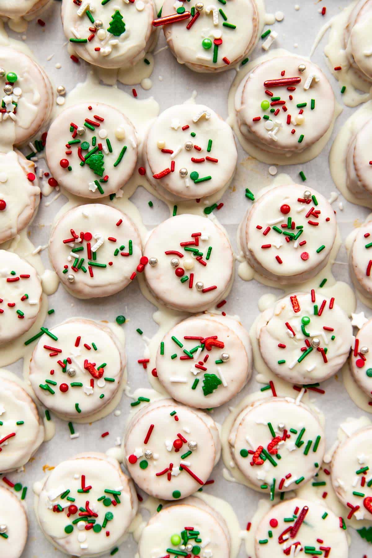 ritz cracker cookies with white icing and christmas sprinkles on a sheet