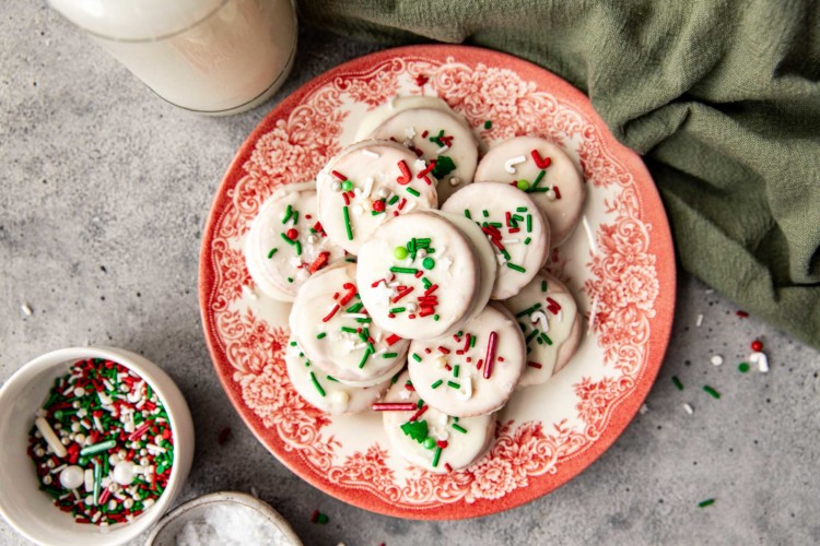 ritz cracker cookies with white icing and christmas sprinkles on a white plate