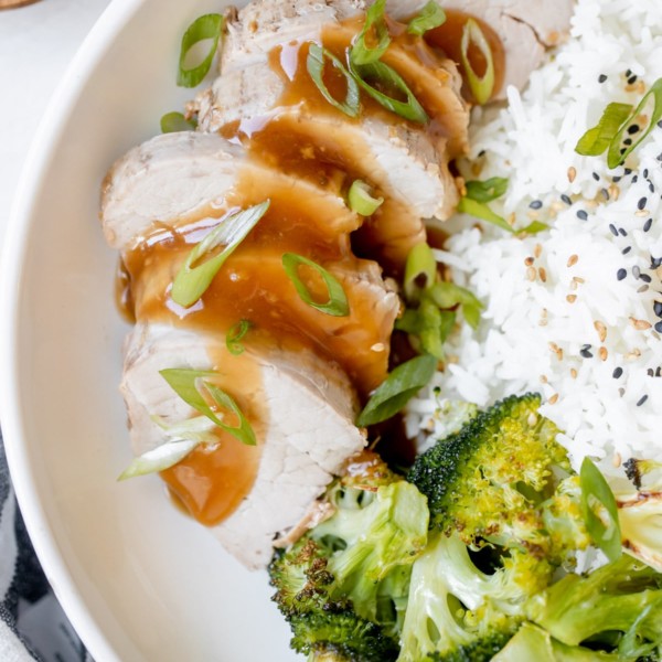 pork tenderloin in a white bowl with broccoli and rice