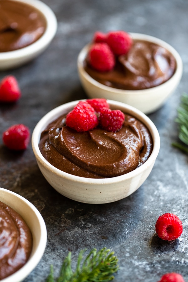 chocolate mousse made with medjool dates in a white bowl topped with raspberries 