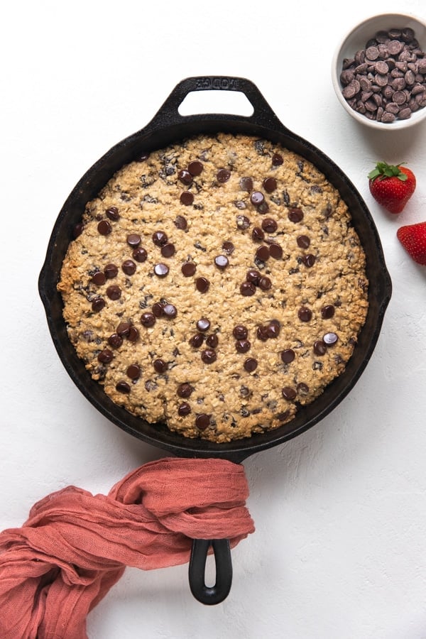 a chocolate chip cookie skillet in a cast iron skillet with strawberries 