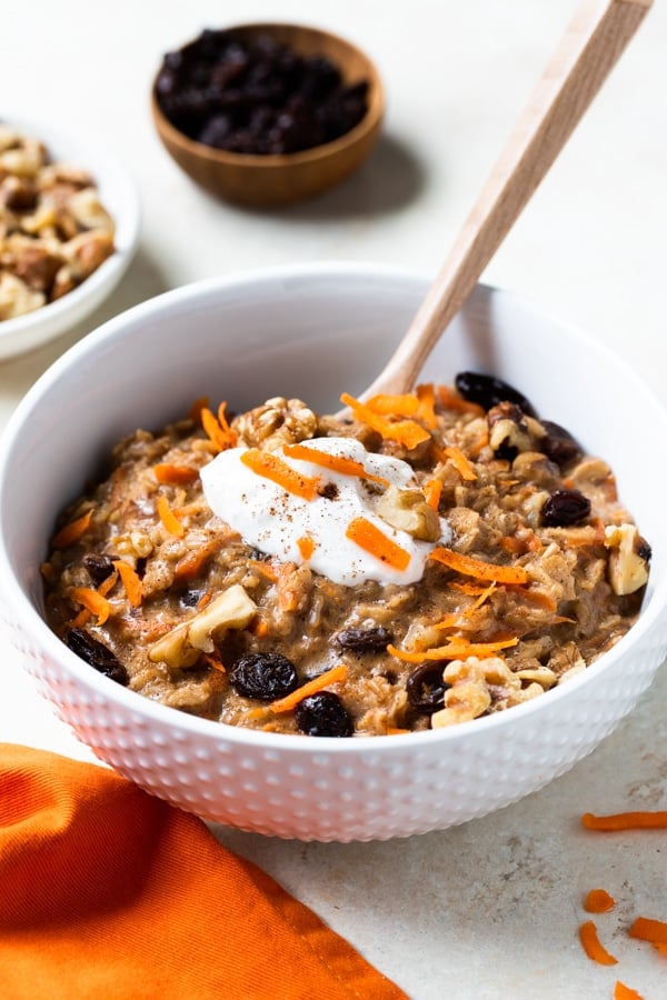 carrot cake oatmeal in white bowls topped with yogurt and shredded carrots 