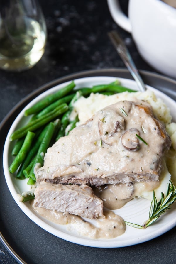 pork chops on a white plate with mashed potatoes and green beans 