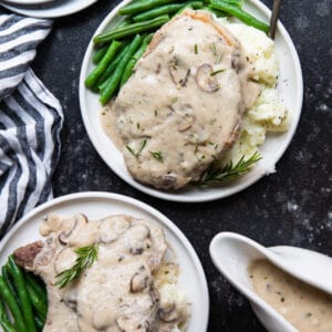 bone in pork chops with mashed potatoes and green beans on a white plate