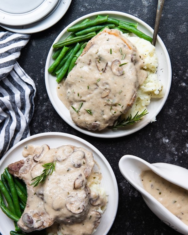 bone in pork chops with mashed potatoes and green beans on a white plate