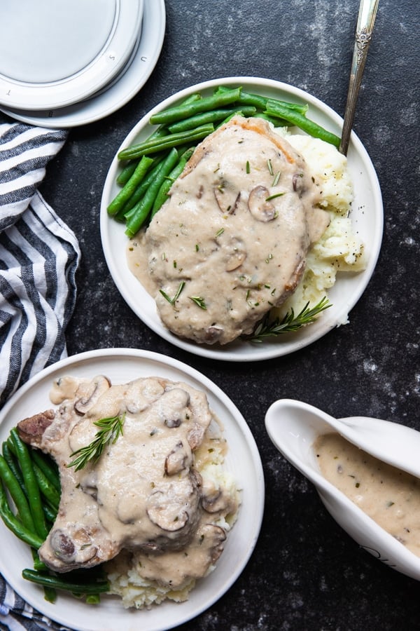 bone in pork chops with mashed potatoes and green beans on a white plate