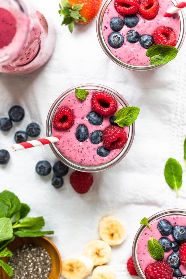 a berry smoothie in a glass topped with fresh berries