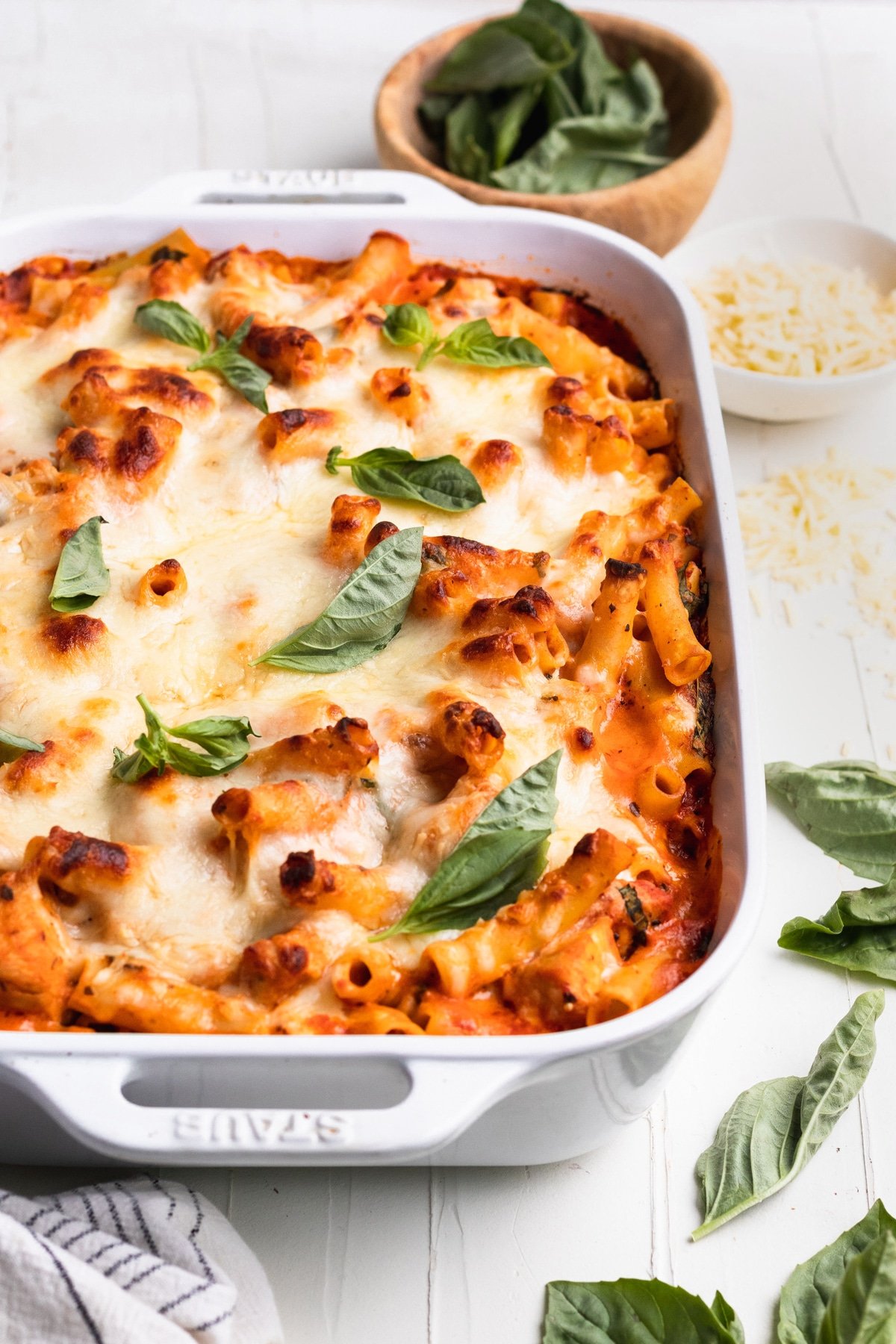 ziti casserole in a white baking dish topped with basil