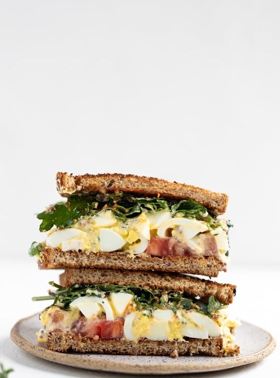 egg salad sandwich with baby kale, tomatoes and hot sauce