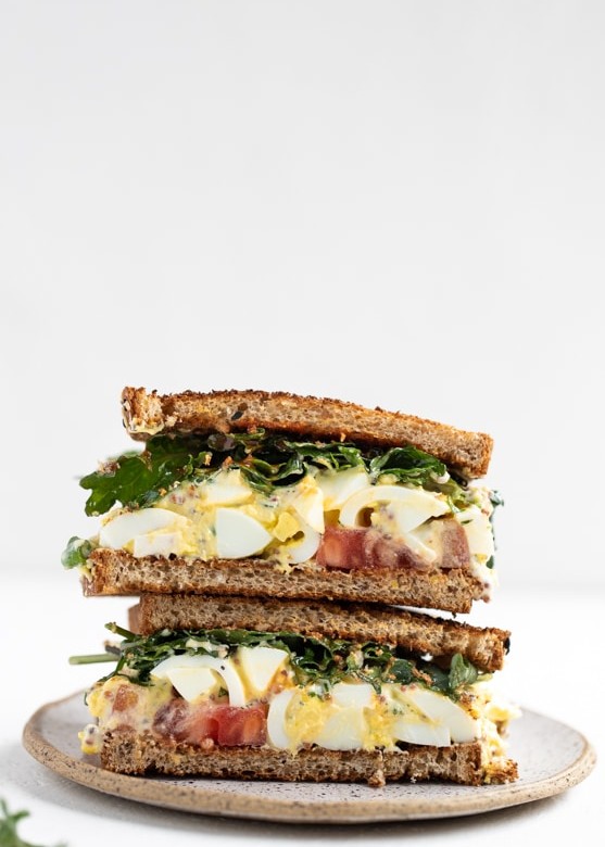 egg salad sandwich with baby kale, tomatoes and hot sauce