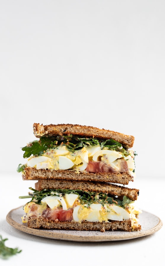 egg salad sandwich with baby kale, tomatoes and hot sauce