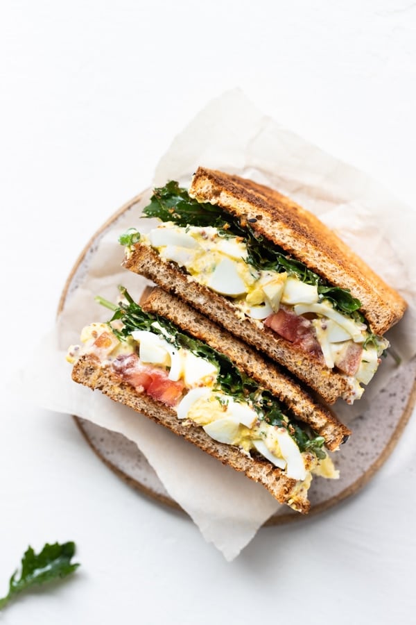 egg salad sandwich on wheat bread with baby kale, Dijon and heirloom tomatoes