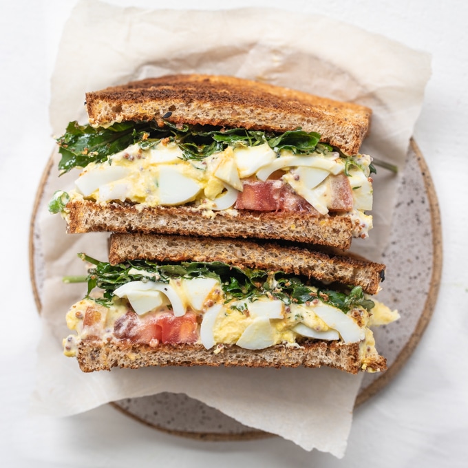 egg salad sandwich on wheat bread with baby kale, Dijon and heirloom tomatoes